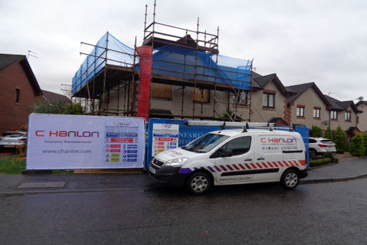 External view of house with scaffolding and C Hanlon liveried van and safety fencing with banners.