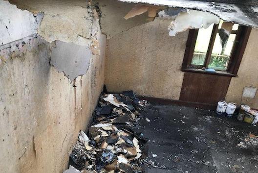 Internal view of fire-damaged room with insecure ceiling, damaged walls and debris on blackened floor. Case study Farm Outbuilding Roof Repair Central Scotland