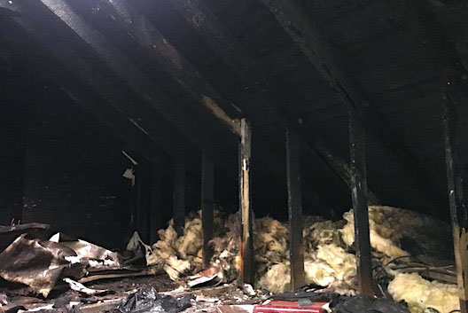 Internal view of fire-damaged roof with blackened beams, rockwool and debris. Case study Fire Damaged House Roof Repair Paisley.