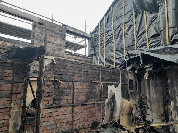 External view of a house that has suffered fire damage featuring exposed blackened brickwork, bare ceiling, protective plastic sheets and scaffolding. case study Fire Damaged Property Restoration Cumnock