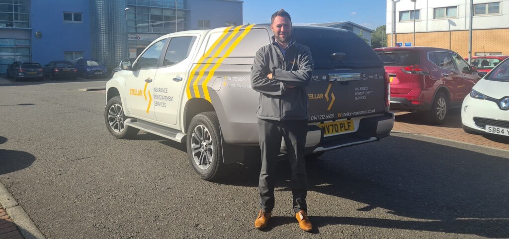Ross Cooper standing with his arms crossed in front of a Stellar insurance liveried truck.