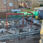 In progress site with concrete blocks, cement mixer and metal structures in place. new build blog