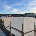 View from roof of house overlooking new roof build, scaffold, neighbouring houses and fields in background. new build blog