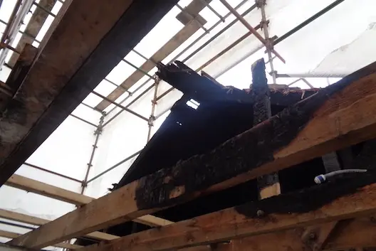 View of fire damaged roof with blackened beams and scaffold surrounding it. Case study of Fire Damaged Roof Repair Glasgow. insurance reinstatement services Glasgow