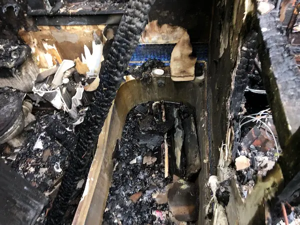 Bird's eye view of fire-damaged bath with blackened walls and surfaces, with debris all over the room and surrounding area.